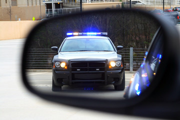 Side mirror police car flashing lights traffic stop